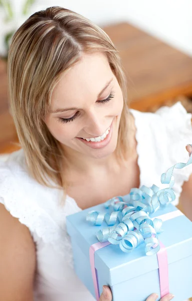 Elinde hediyeyle yerde oturan mutlu genç bir kadın. — Stok fotoğraf