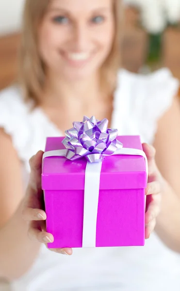 Young woman holding a present sitting on the floor — Stock Photo, Image