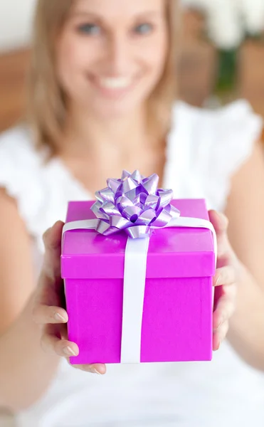 Mujer joven sosteniendo un regalo sentado en el suelo — Foto de Stock