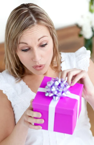 Şaşırmış kadın katta oturan bir hediye açılış — Stok fotoğraf