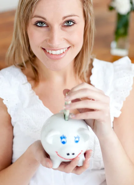Mulher brilhante economizando dinheiro em um banco porquinho — Fotografia de Stock