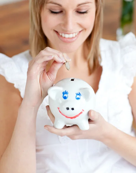 Mulher alegre economizando dinheiro em um banco porquinho — Fotografia de Stock