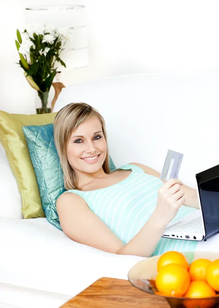 Mujer feliz de compras en línea acostado en un sofá — Foto de Stock