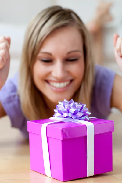 Šťastná žena při pohledu na dárek leží na podlaze — Stock fotografie