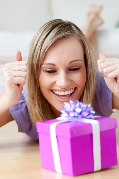 Радостная женщина смотрит на подарок, лежащий на полу — стоковое фото