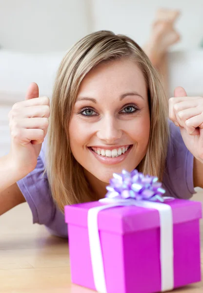 Excited woman looking at a gift lying on the floor — Stock Photo, Image