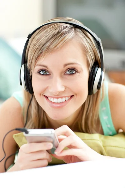 Charming young woman listening music lying on a sofa — Stock Photo, Image