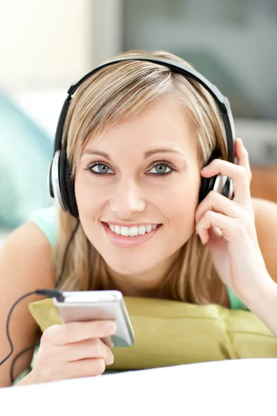 Attractive young woman listening music lying on a sofa — Stock Photo, Image