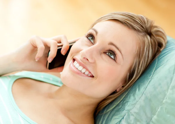 Vrolijke jonge vrouw praten over telefoon liggen op een sofa — Stockfoto