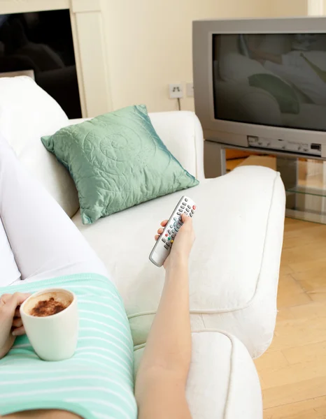 Woman drinking a coffee while watching TV — Stock Photo, Image