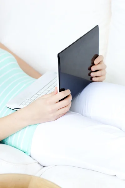 Κοντινό πλάνο του μια γυναίκα χρησιμοποιώντας ένα φορητό υπολογιστή που βρίσκεται σε έναν καναπέ — Φωτογραφία Αρχείου