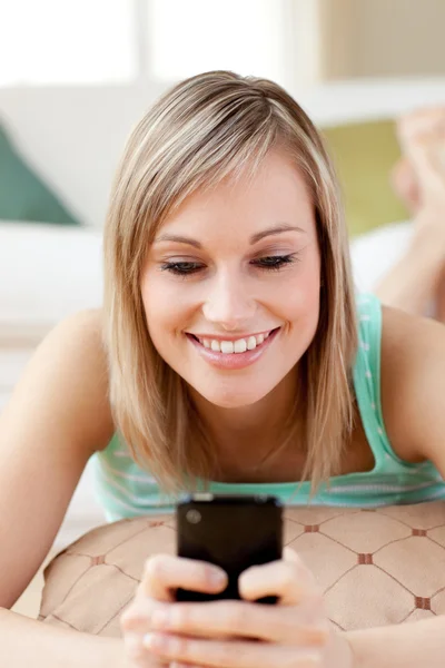 Glad kvinna skicka en text som ligger på golvet — Stockfoto