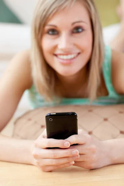 Attraktive blonde Frau schickt einen Text auf dem Boden liegend — Stockfoto