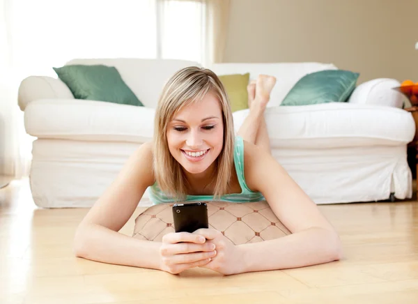 Jolly woman sending a text lying on the floor — Stock Photo, Image