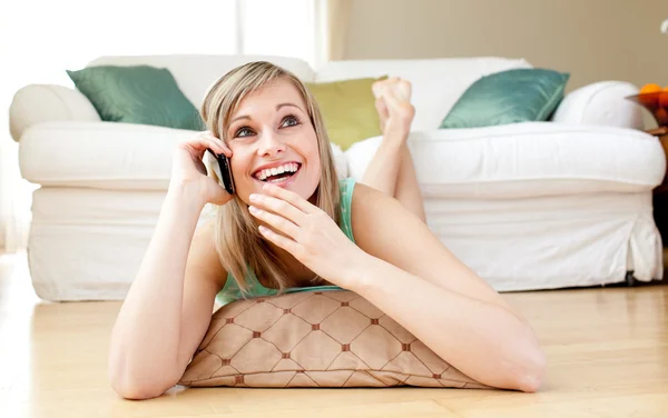Laughing young woman talking on phone lying on the floor — Stock Photo, Image