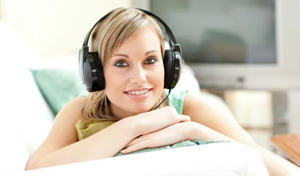 Boldog fiatal nő hallgat zenét a kanapén feküdt — Stock Fotó