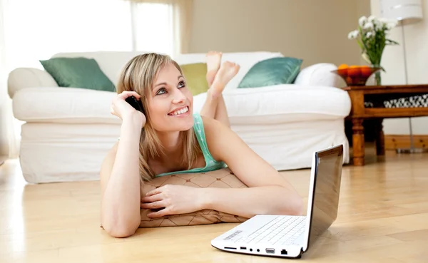 Happy woman using a laptp lying on the floor — Stock Photo, Image