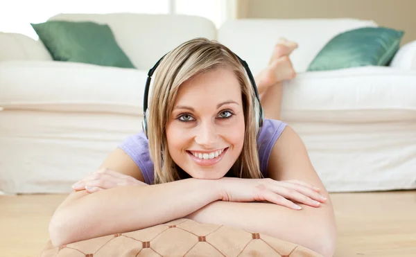 Stralende vrouw luisteren muziek op de vloer liggen — Stockfoto