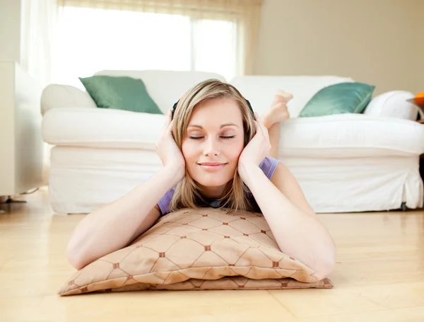 Attraktive Frau, die auf dem Boden liegend Musik hört — Stockfoto