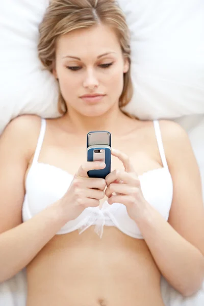 Concentrated woman in underwear sending a text — Stock Photo, Image