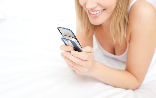 Nahaufnahme einer blonden Frau, die eine SMS im Liegen gibt — Stockfoto