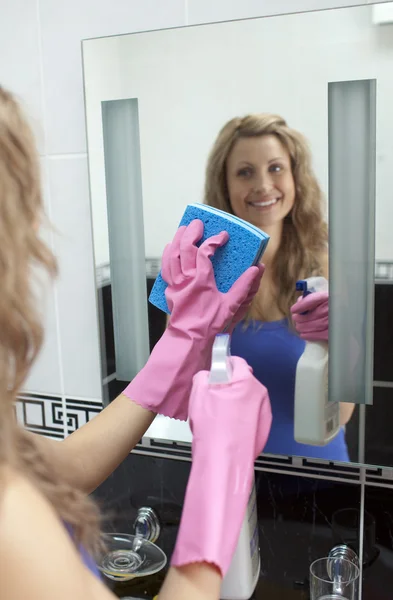 Femme souriante nettoyage miroir de salle de bains — Photo