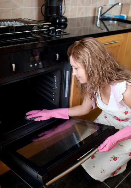 Junge Frau putzt den Ofen — Stockfoto