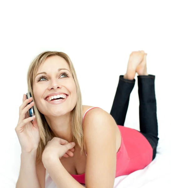 Jolly woman talking on phone lying on a bed — Stock Photo, Image