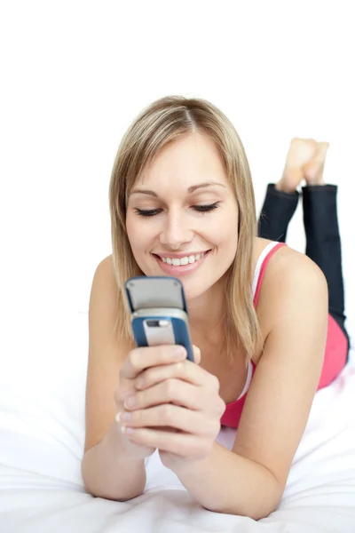 Jasny kobieta wysyłanie tekstu, leżąc na łóżku — Zdjęcie stockowe