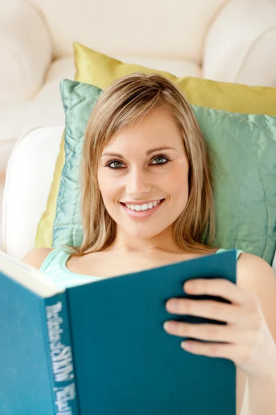 Γοητευτική γυναίκα διαβάζοντας ένα βιβλίο ξαπλωμένη σε ένα καναπέ — Φωτογραφία Αρχείου