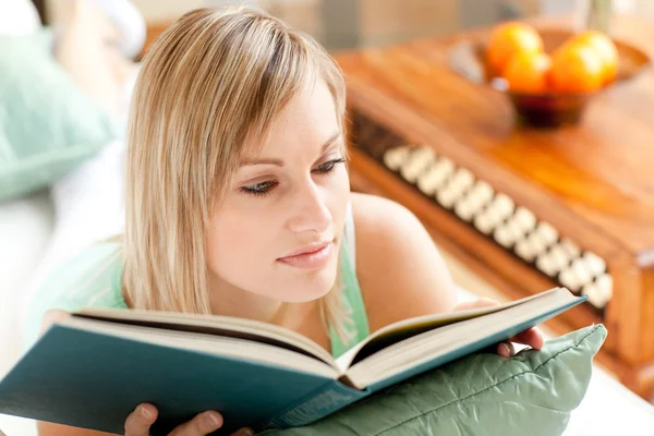 Ciddi kadın kanepede yatan bir kitap okuma — Stok fotoğraf