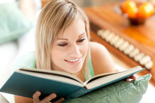 Mulher brilhante lendo um livro deitado em um sofá — Fotografia de Stock