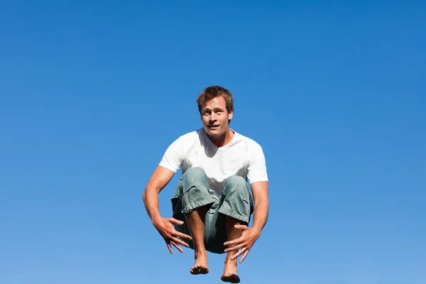 ハンサムな男性は青い背景に対するジャンプ — ストック写真