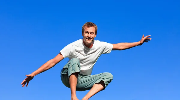 Красивый мужчина прыгает на синем фоне — стоковое фото