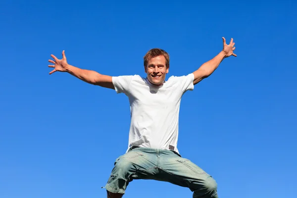 Schöner Mann springt vor blauem Hintergrund — Stockfoto