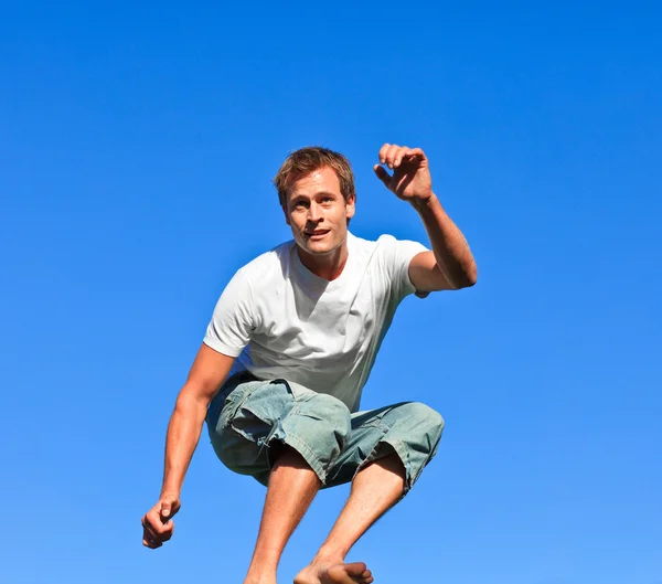 Homme souriant sautant sur un fond bleu — Photo