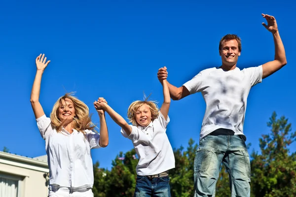 Glückliche Familie springt vor blauem Hintergrund — Stockfoto