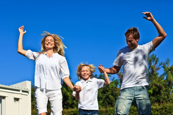 Счастливая семья прыгает на голубом фоне — стоковое фото