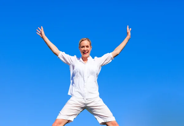 Щаслива жінка стрибає на блакитне небо — стокове фото