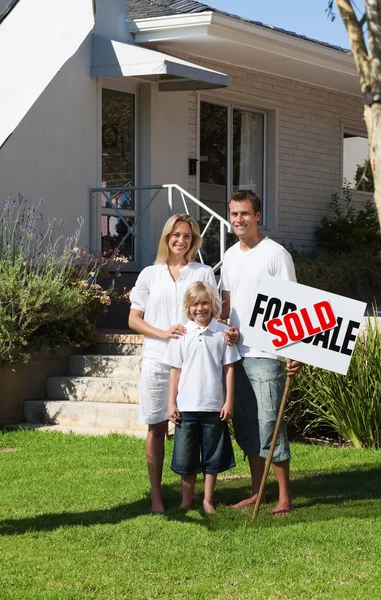 Gelukkige familie met hun nieuwe huis in de tuin — Stockfoto