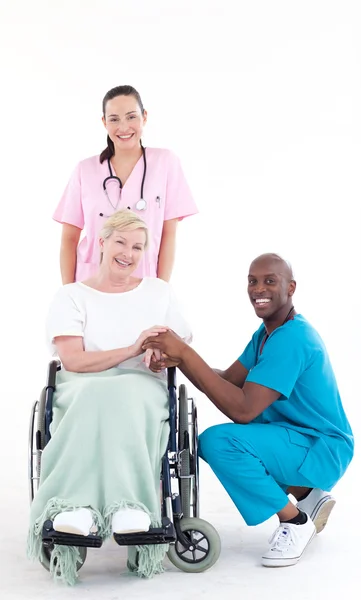 Ärzte mit einem Patienten im Rollstuhl lächeln in die Kamera — Stockfoto
