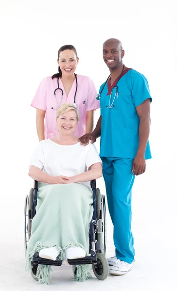 Enfermera y médico cuidando a un paciente en silla de ruedas — Foto de Stock