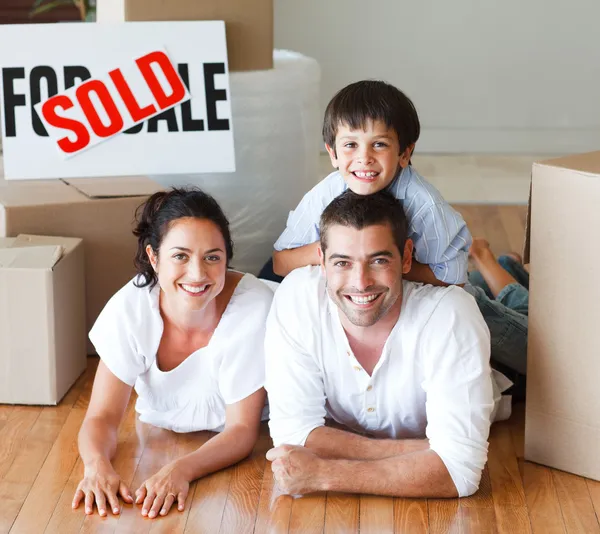 Familie op de verdieping glimlachen in de camera na het kopen van huis — Stockfoto