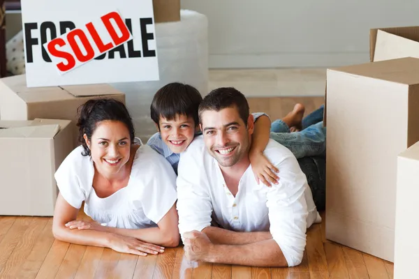 Famiglia felice sdraiata sul pavimento dopo l'acquisto di casa con scatole — Foto Stock