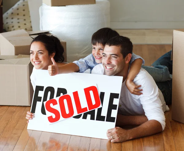 Szczęśliwa rodzina leżącego na podłodze, po zakupie domu z kciukami u — Zdjęcie stockowe