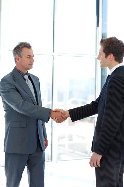Senior and junior businessman shaking hands in agreement — Stock Photo, Image