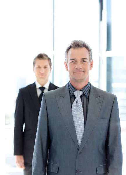 Young and senior businessmen standing in front of the camera — Stockfoto