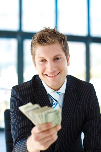 Junior businessman holding dollars and smiling at the camera — Stock Photo, Image