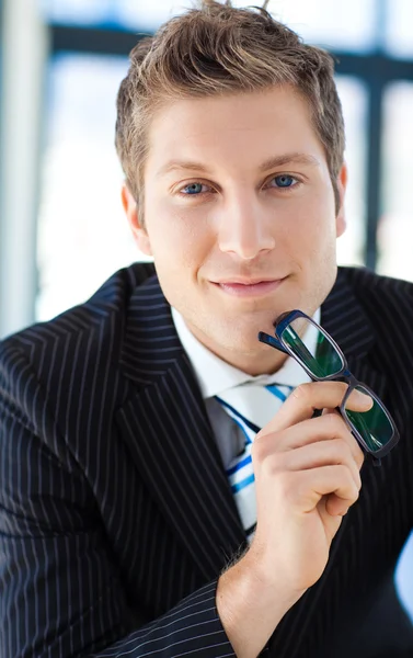 Businessman looking to the camera holding glasses — Stock Photo, Image