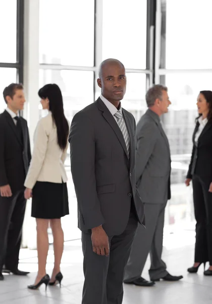 Serious business leader looking at camera in front of team — Stock Photo, Image